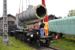 Langsam wird der am Arm des Pneukrans schwebende Kessel auf den darunter stehenden Rahmen abgesenkt. Je 2 Helfer vorne und hinten richten den Kessel aus. Sulgen 16. Mai 2014 | Bild: M. Simmons
