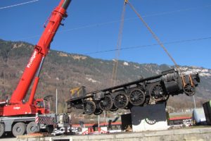 Der durch den Werkstatt-Brand beschädigte Rahmen unserer C 5/6 2969 wird vor der Bergkulisse Interlakens mit einem Pneukran angehoben um auf einen Strassentieflader abgesetzt zu werden, 17.12.2013 | Bild: Riccardo Keller