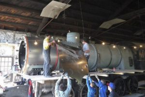 Spenglerlehrlinge der Berufsschule Rorschach hieven mit vereinten Kräften ein neues, grosses Blechteil für die Kesselverkleidung der C 5/6 2969 auf den Kessel. In der Lokremise Sulgen 01.07.2014 | Bild: Josef Angehrn