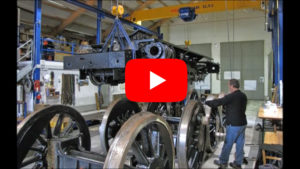 Standbild Rahmen in der Luft wird per Kran zu den aufgegleisten Treibachsen verschoben. Depot Interlaken | Bild: Riccardo Keller / EV