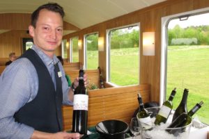 Ein Mitarbeiter der Landi Weinland präsentiert eine Flasche Wein im fahrendend "Weinkeller" BDe 3/4 43. 01. Mai 2017 | Bild: H.U. Kneuss